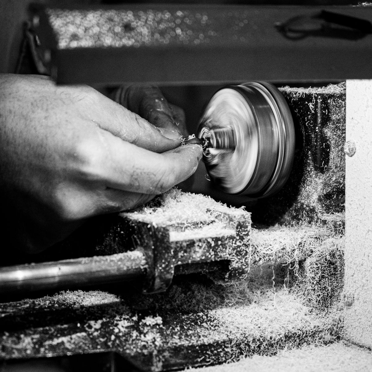 Main d'un artisan maniant un outil de meulage sur une pièce en atelier de précision