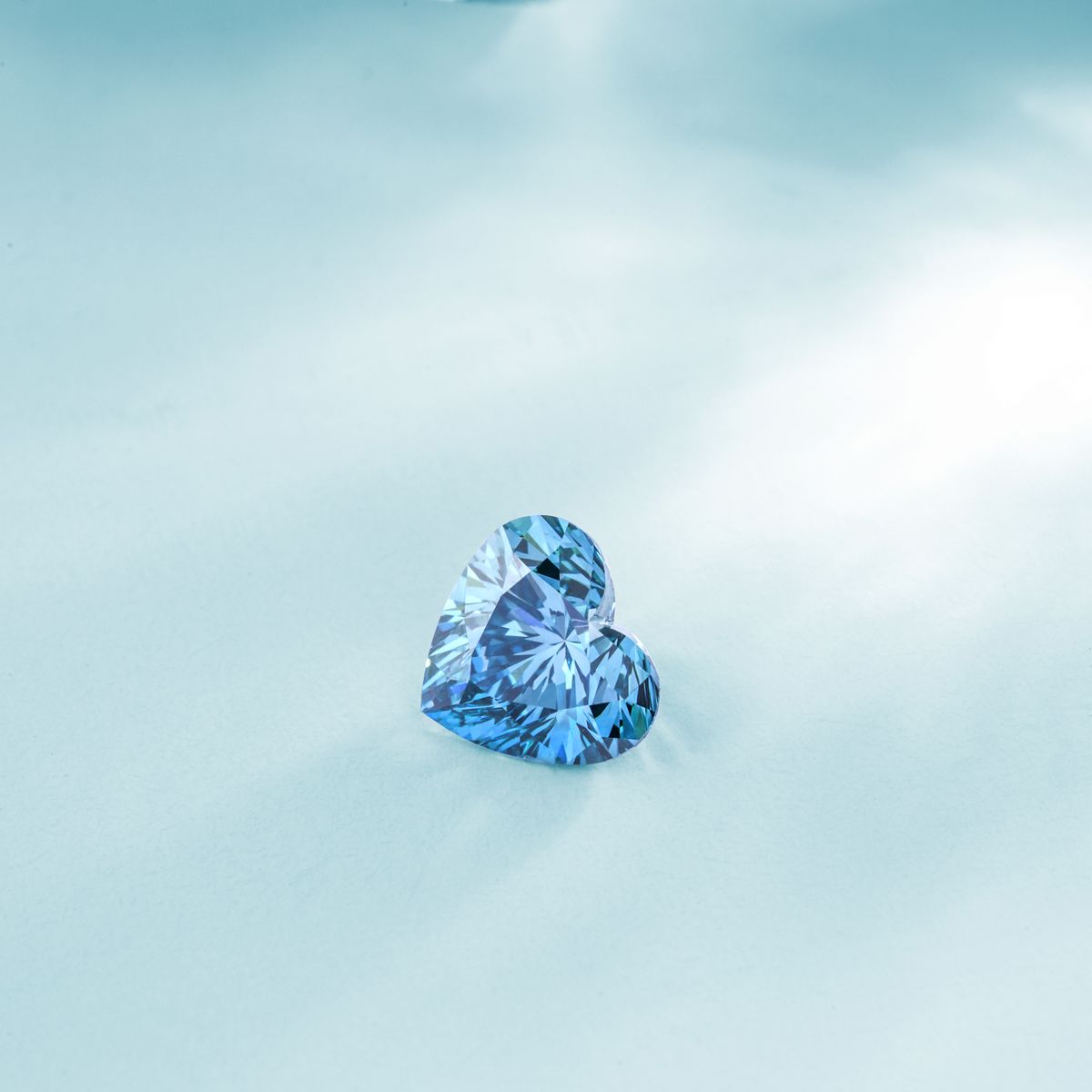 Gemme bleue transparente illustrant un monocristal proche du saphir sur fond bleu clair
